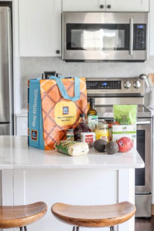 An aldi bag on the counter in a kitchen with a variety of groceries.