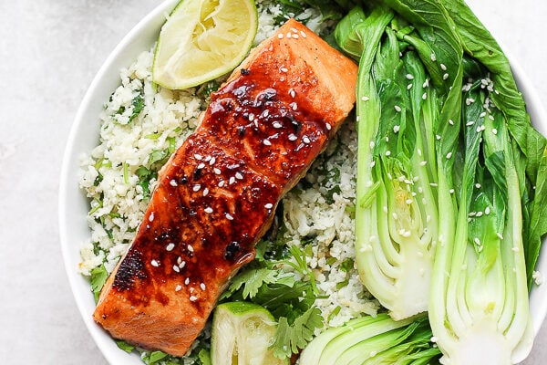 Sesame ginger salmon fillet in a bowl with cilantro lime cauliflower rice and braised bok choy.