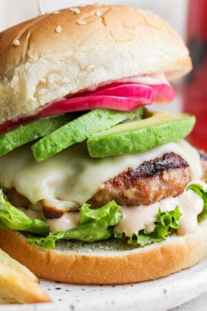 Avocado turkey burger on a bun on a plate with fried.