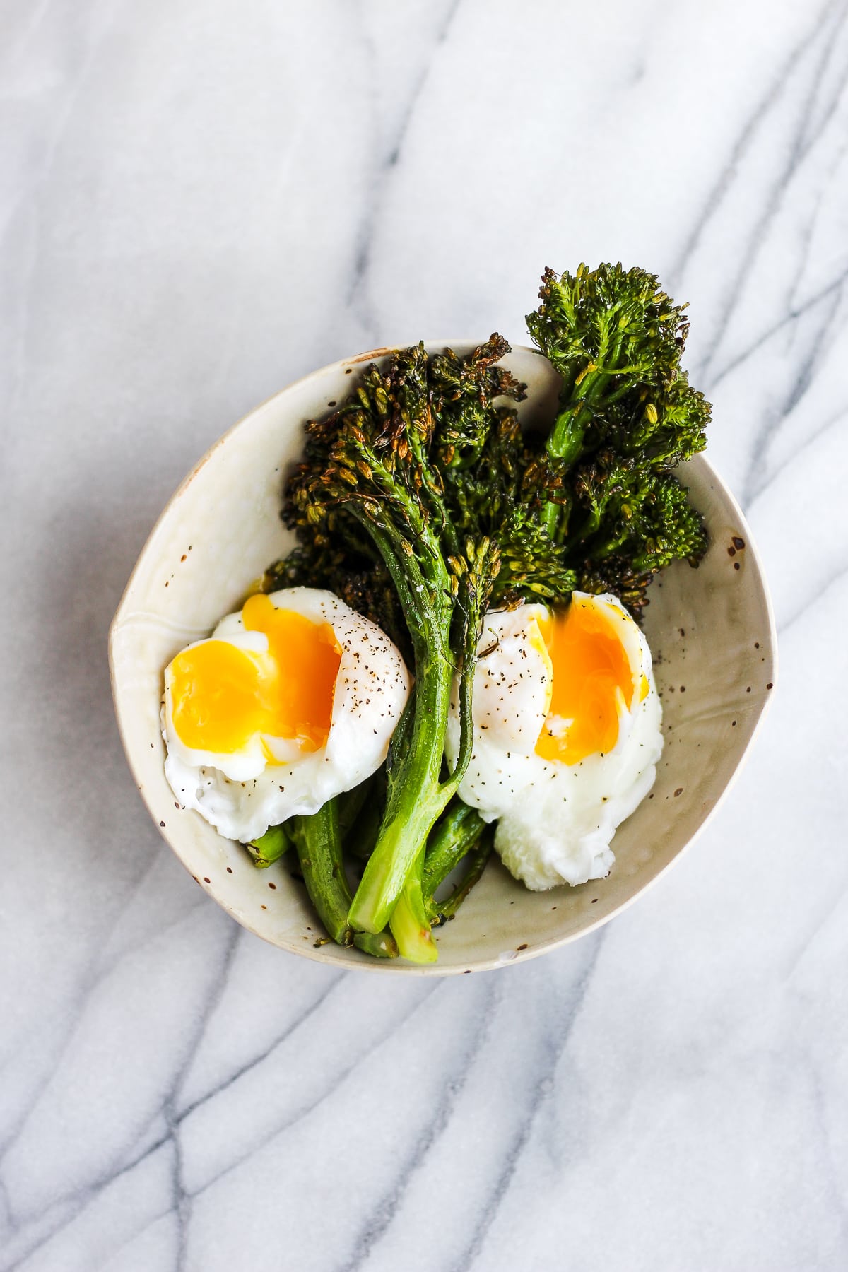 Whole30 Weekly Menu Plan - a weeks worth of breakfast, lunch, dinner and snack! #whole30 #whole30weeklymealplan #weeklymealplan #whole30recipes Roasted broccolini in a bowl with two poached eggs.