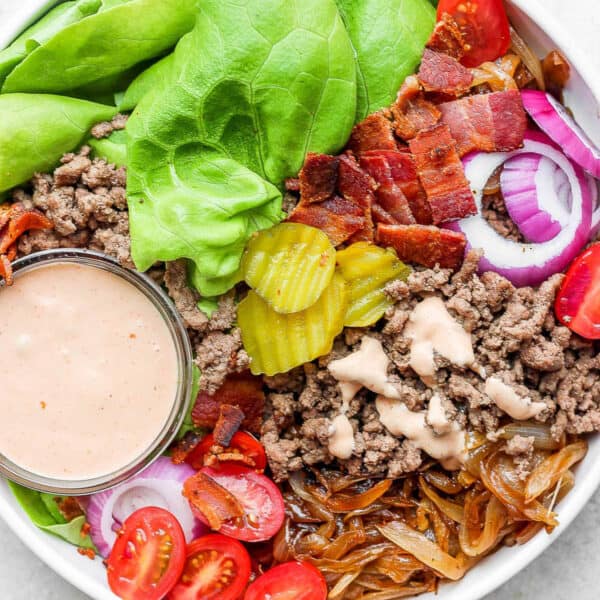 A Burger Bowl filled with burger sauce, lettuce, pickles, bacon, tomatoes and caramelized onions.