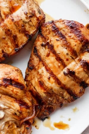 A plate of grilled chicken breasts with grill marks.