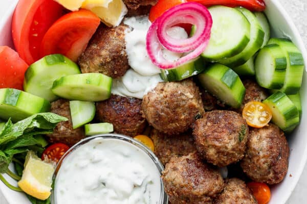 A simple gyro bowl with meatballs, fresh vegetables, and tzatziki sauce.