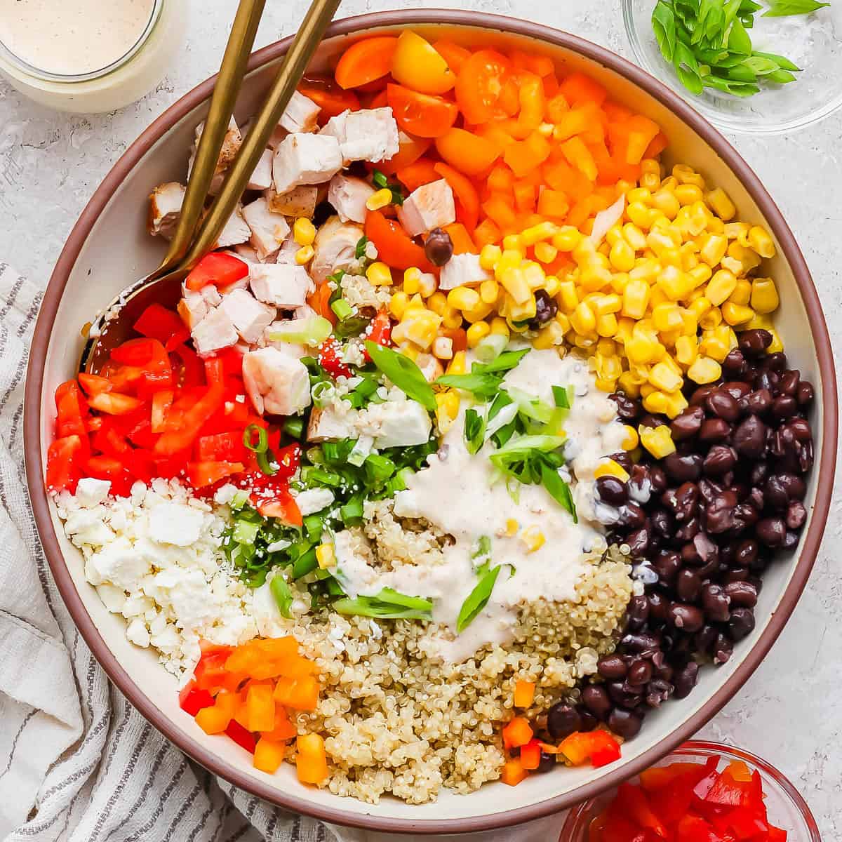 A big bowl of southwest quinoa salad with black beans, corn, bell peppers, feta cheese and a creamy southwest dressing on top.