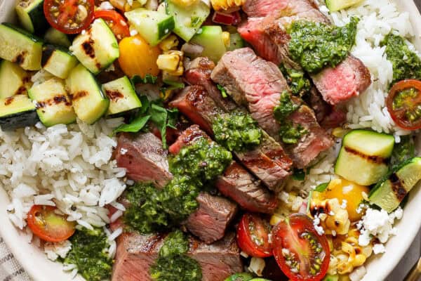 Close-up image of a steak rice bowl with chimichurri sauce.